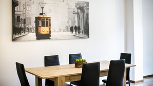 Un comedor con una mesa de madera, sillas negras y una fotografía en blanco y negro de un tranvía en la pared.