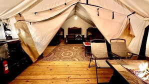 A tented room with a wooden floor, a fire pit, and a patterned rug. - Maples Farm Fresh Eggs (Nashville)