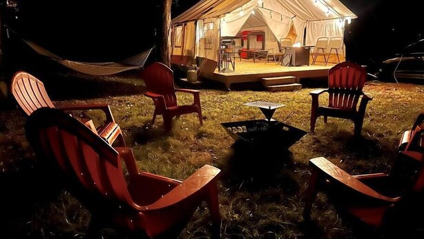A tented outdoor area with a dining setup, red chairs, and a fire pit. - Maples Farm Fresh Eggs (Nashville)