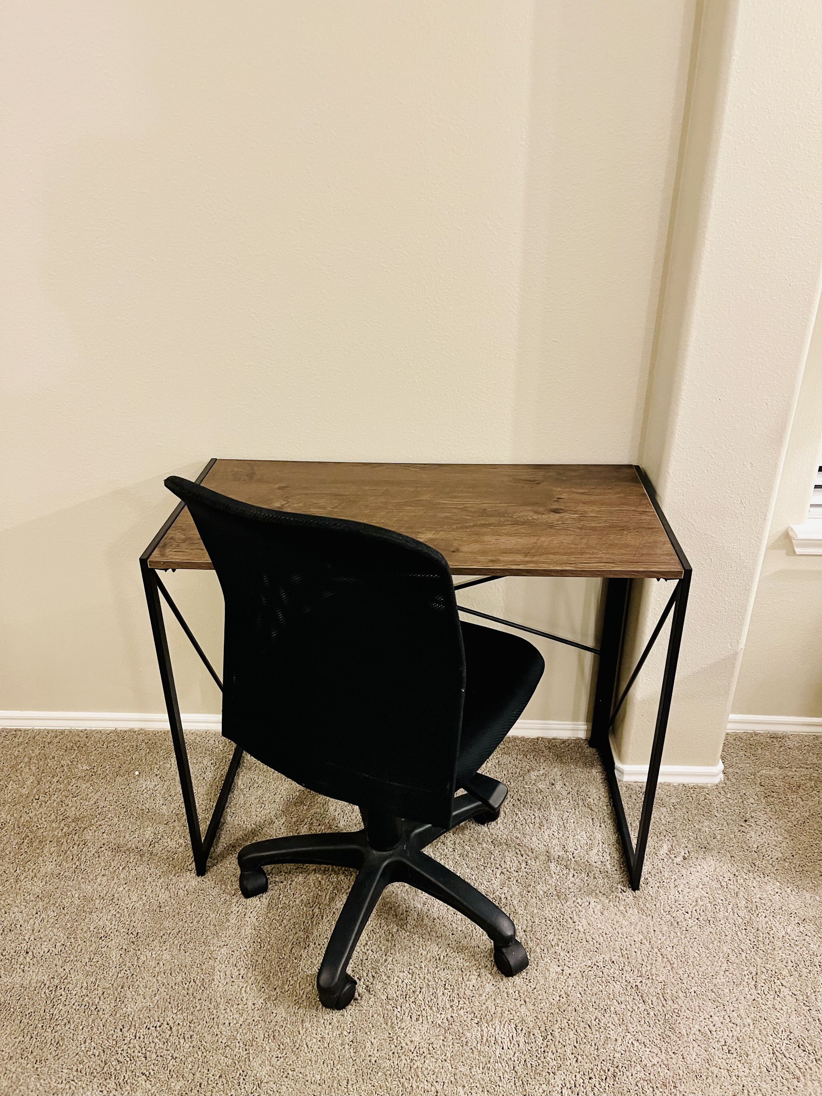 Un bureau d’angle avec un bureau en bois et un fauteuil de bureau noir.