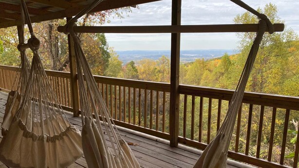 A wooden deck with two hammocks hanging from the ceiling, overlooking a forested landscape. - Secluded 1 bd 2 bath cabin with Great View (Sevier County)