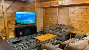A cozy cabin interior with a wooden staircase, a television, a sofa, and a coffee table. - Secluded 1 bd 2 bath cabin with Great View (Sevier County)