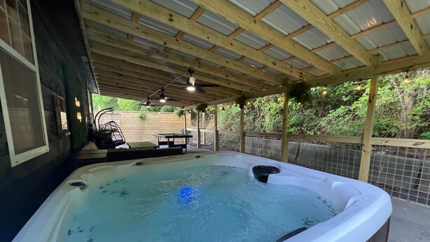 A hot tub under a wooden pergola with a wooden fence and greenery in the background. - Flat Fenced yard, hot tub , wifi, pool table (Sevier County)