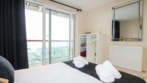 A hotel room with a bed, a wardrobe, a mirror, and a view of the city through the window. - Bear's Apartment (Portland)