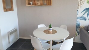 En matplats med ett runt, vitt bord, vita stolar, en liten kaktus och en trähylla med en solros.