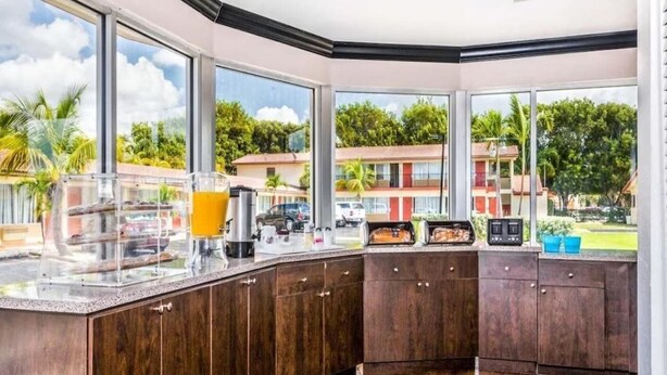Une cuisine dotée d’une grande fenêtre, de meubles en bois et d’un bar pour prendre le petit-déjeuner, agrémenté de divers éléments.