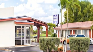 Un hôtel au design moderne, doté d’une entrée couverte, d’une voiture garée devant et d’une pelouse bien entretenue.