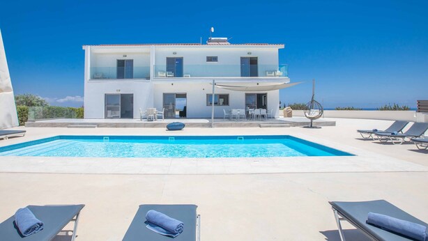 A two-story building with a swimming pool and lounge chairs. - Villa Demeter GA98 - Six Bedroom Villa, Sleeps 12 (Paralimni)