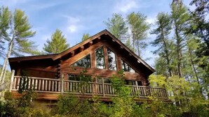 Een houten hut met een balkon, omringd door dicht bos.
