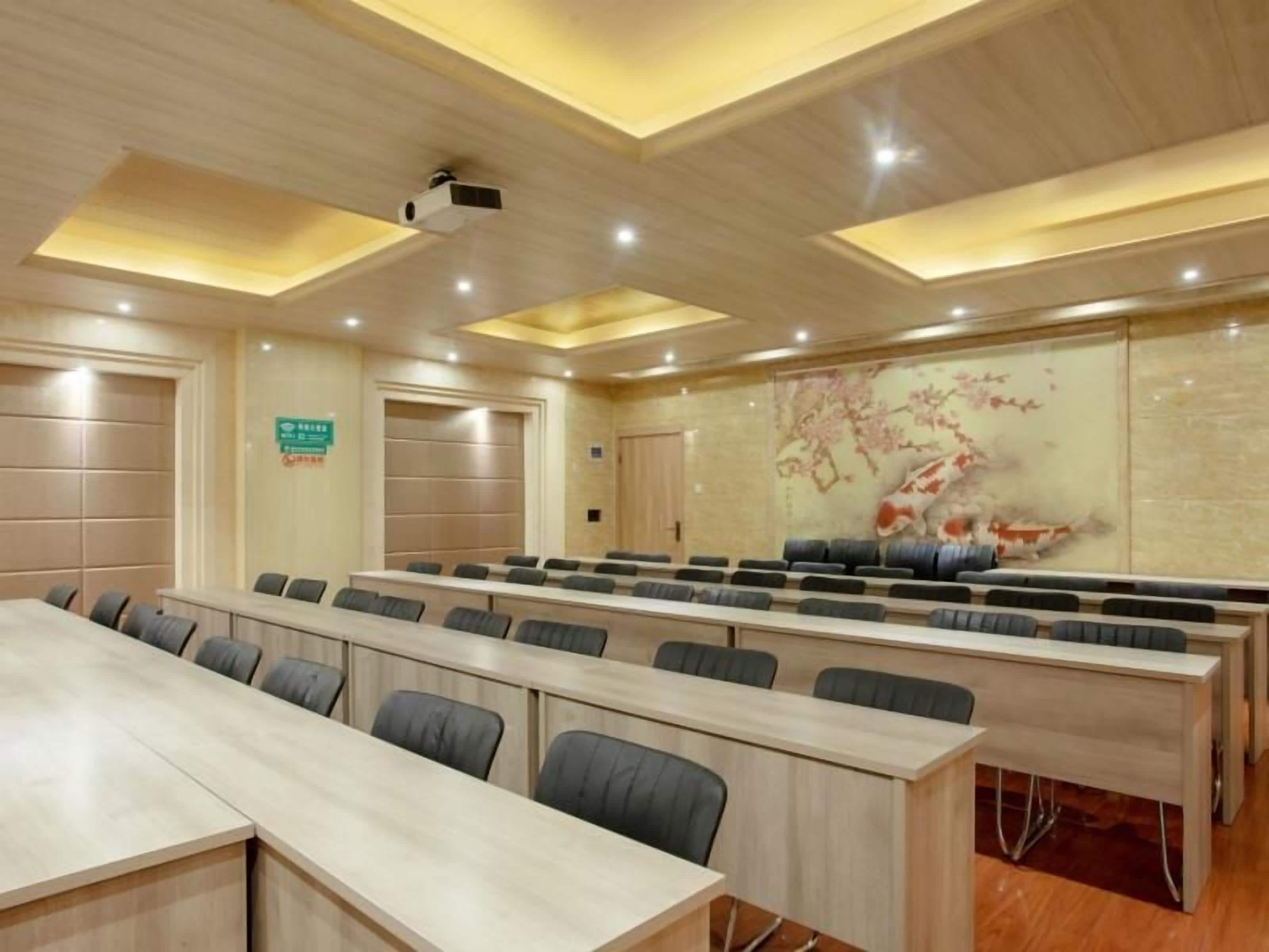 A conference room with long tables and chairs, a projector, and a decorative wall with a koi fish painting.