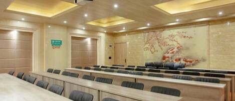 A conference room with long tables and chairs, a projector, and a decorative wall with a koi fish painting.