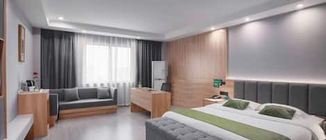 A modern hotel room with a bed, a sofa, a desk, and a wardrobe.