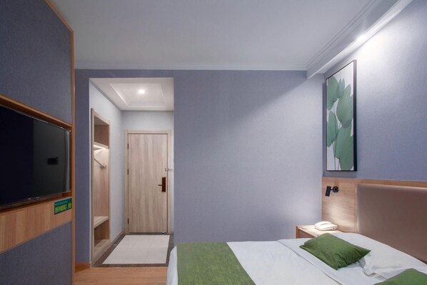 A hotel room with a bed, a bedside table with a phone, a TV mounted on the wall, and a door leading to a bathroom. - Greentree Inn Anhui Hefei South High-speed Rail Station Fanhua Avenue Haiheng Express Hotel (Hefei)