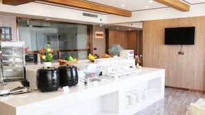 A modern reception area with a white counter, kitchen appliances, and a flat-screen TV on the wall. - Greentree Alliance Laizhou Bus Station Wenhua West Street (Yantai)