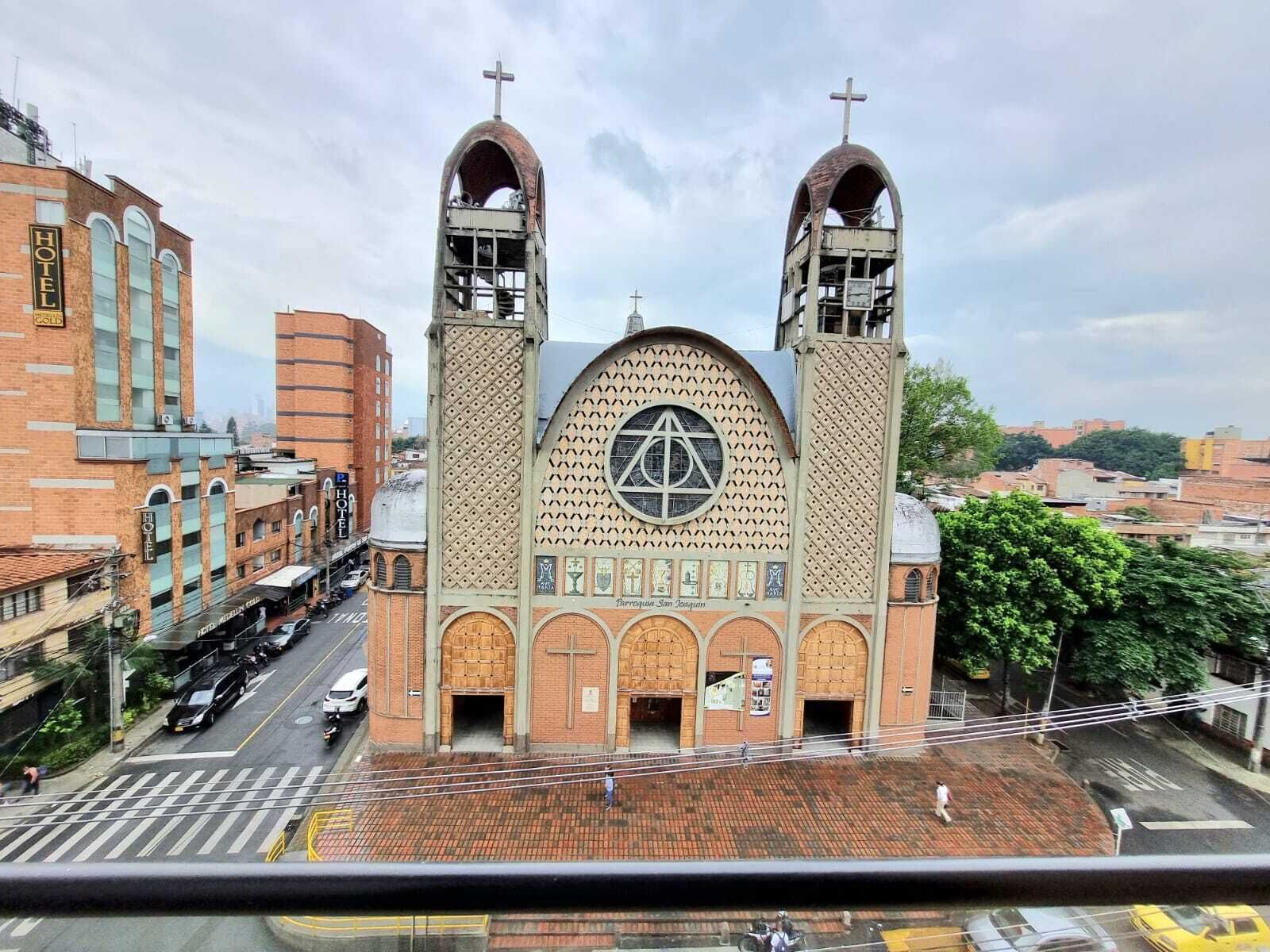 A large building with two prominent towers, a central circular window with a symbol, and a brick facade.
