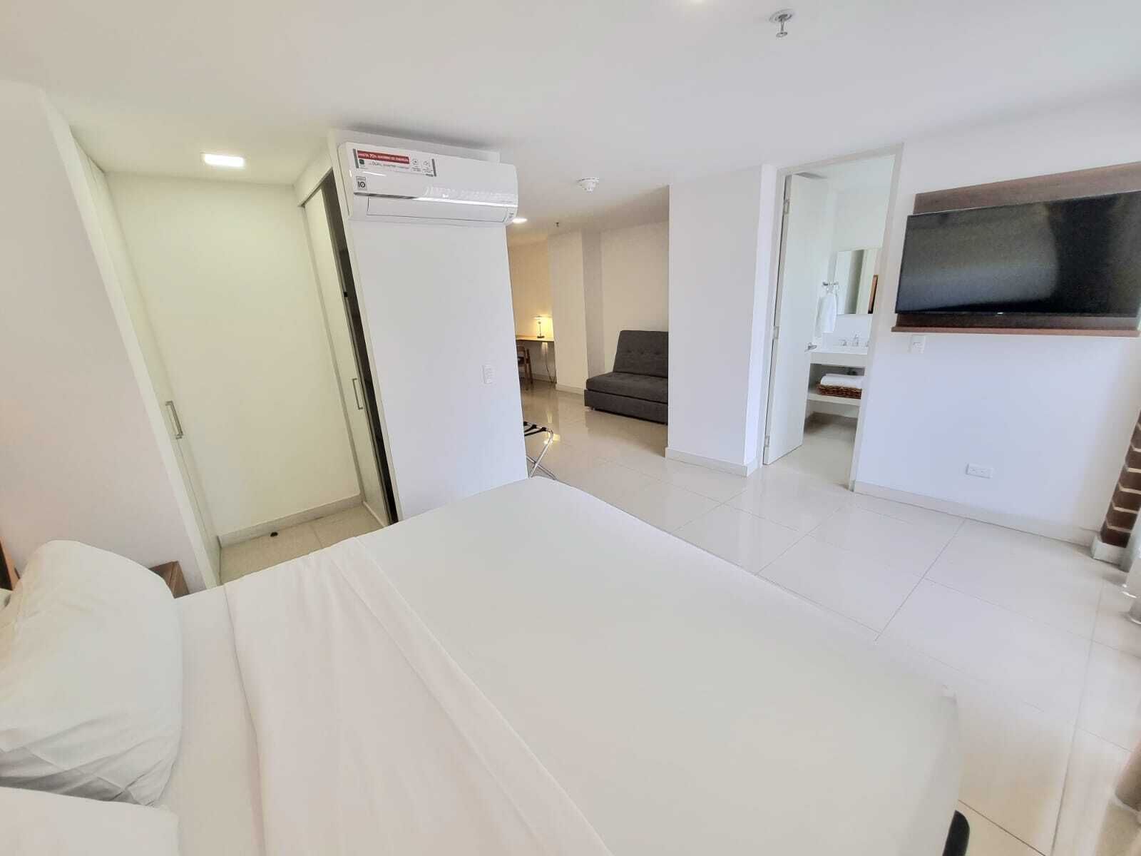 Una habitación de hotel moderna con una cama, un televisor y una zona de estar con un sofá y una mesita.