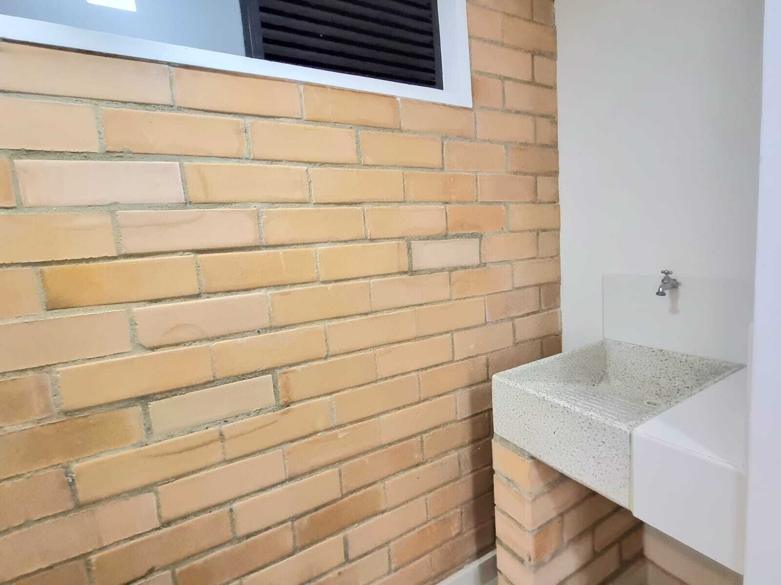 A bathroom with a tiled wall, a window with a vent, and a white sink.