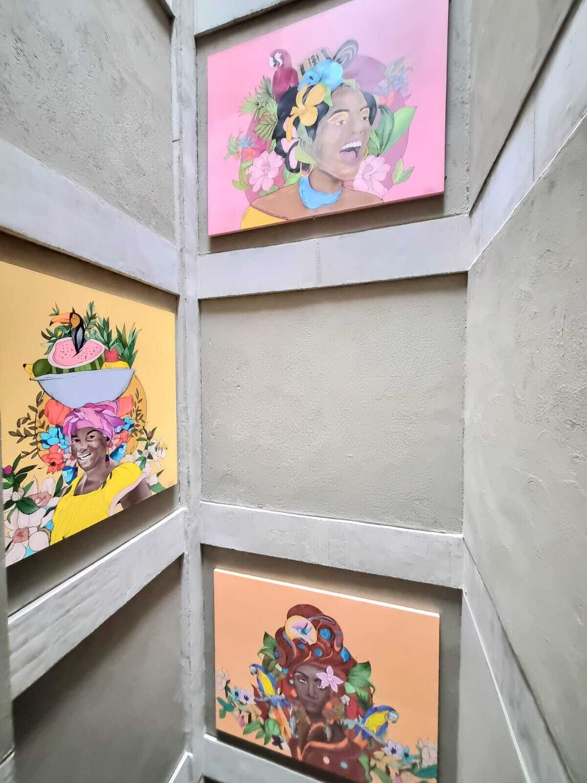 Un mur orné de trois œuvres d’art encadrées représentant des scènes florales et de fruits aux couleurs vives.