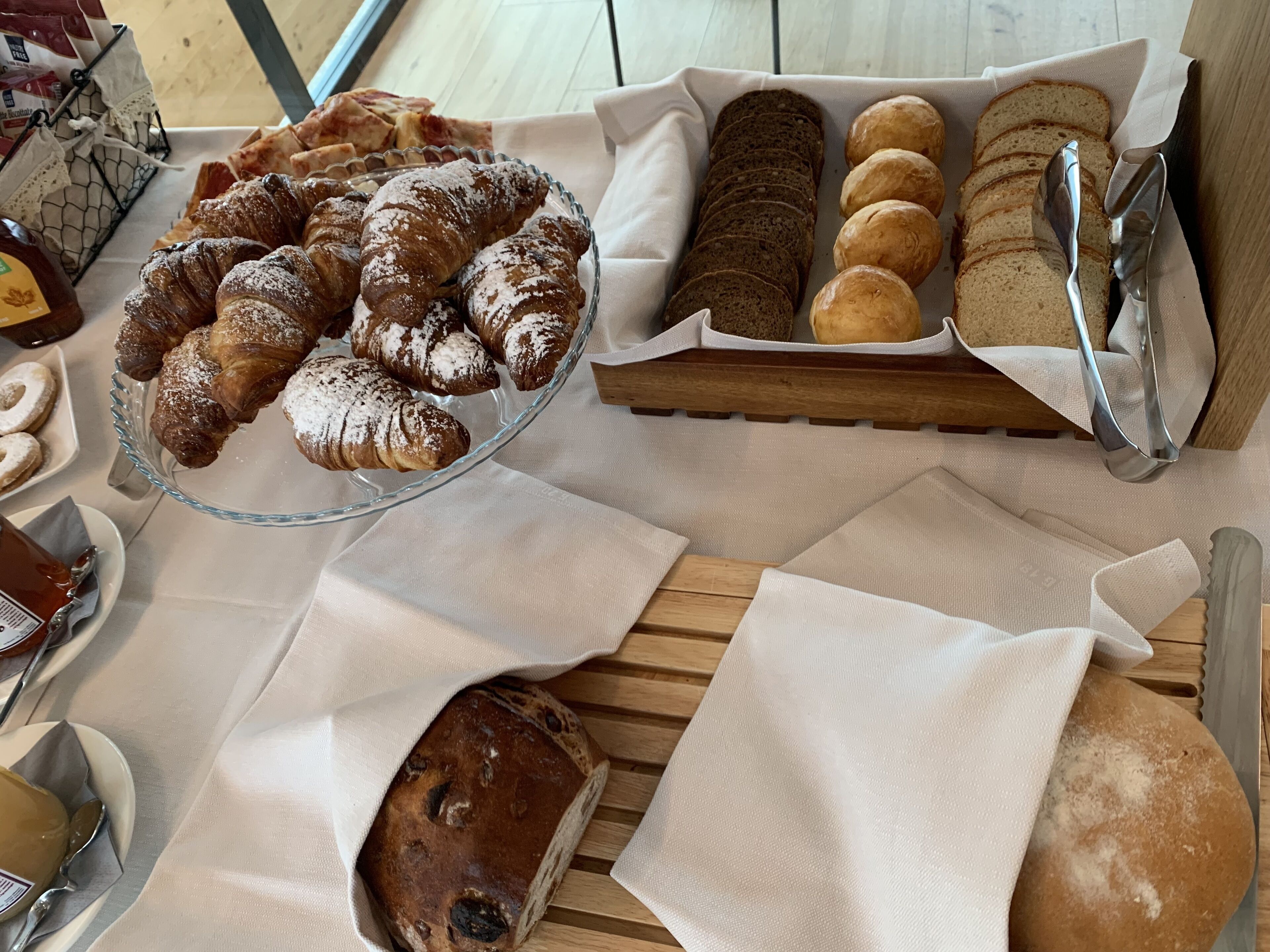 A variety of baked goods including croissants, bread, and rolls on a wooden table.