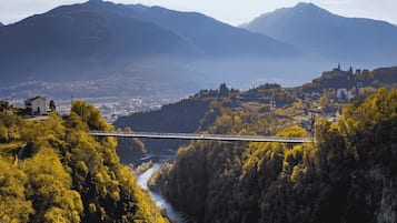 Eine Brücke über einem Fluss, darunter ein Tal mit einer Stadt, umgeben von Bergen.