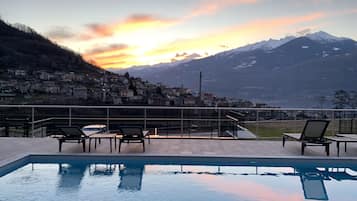 Una piscina al aire libre, sillones reclinables de piscina