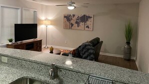 Een moderne woonkamer met een granieten aanrechtblad, een flatscreen televisie, een plafondventilator en een wereldkaart als kunstwerk aan de muur.