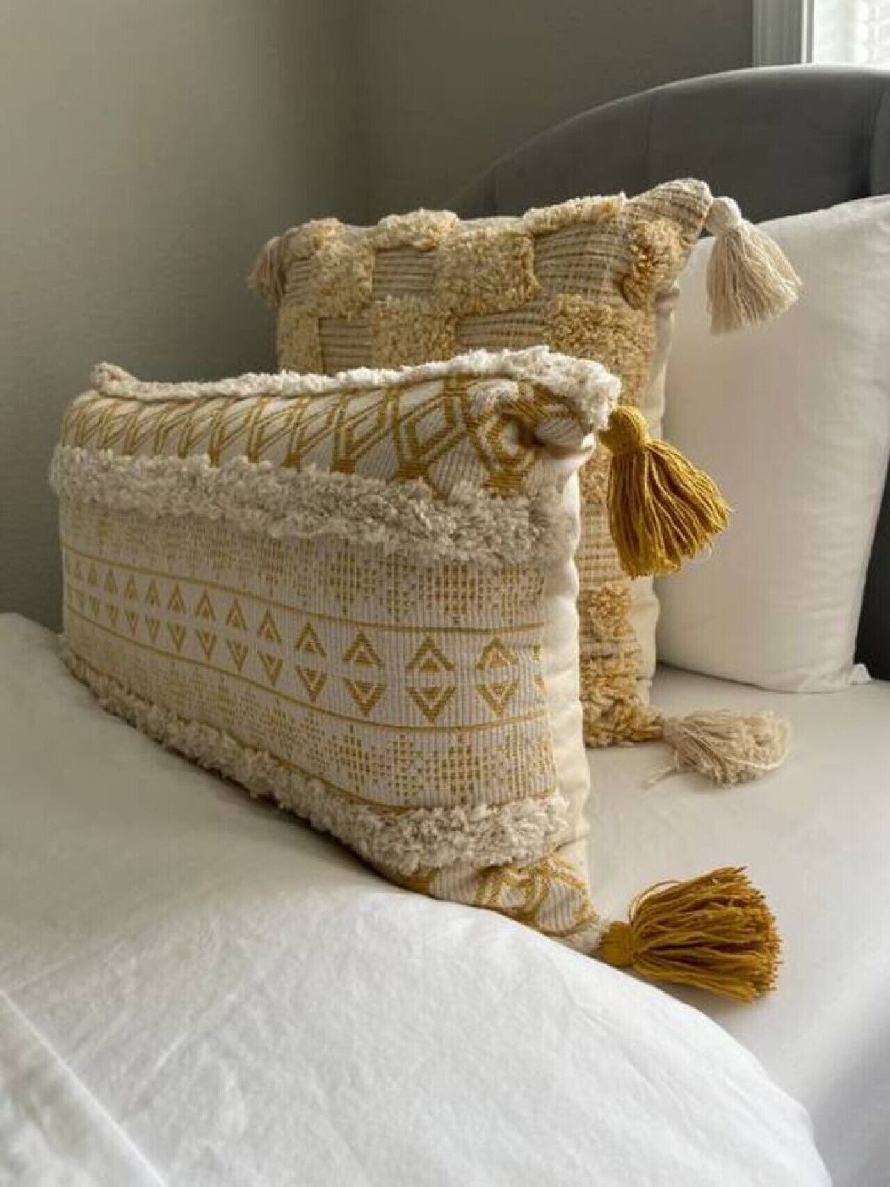 Dos almohadones de crochet con flecos sobre una cama.