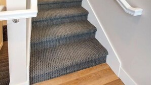 Eine Treppe mit Teppichstufen und einem weißen Geländer.