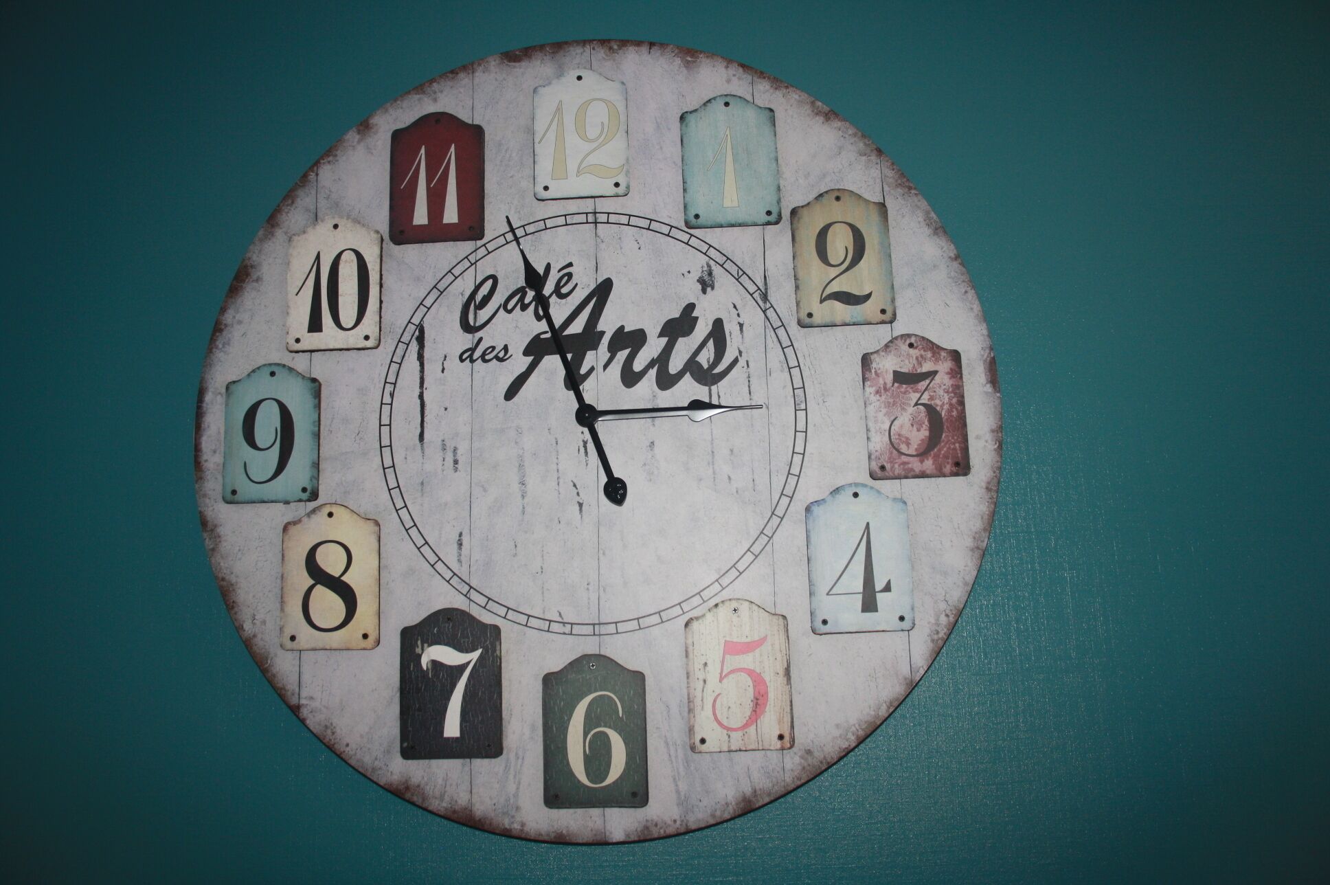 Eine Uhr mit Ziffern und dem Schriftzug "cafe des Arts" auf dem Zifferblatt.