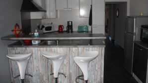 Una cucina moderna con sgabelli da bar bianchi, un forno a microonde, una macchina da caffè e un frigorifero.