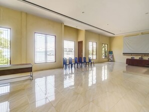A spacious room with large windows, a wooden bench, and a row of blue chairs. - OYO Homes 91148 Homesstay Desa Wisata Bahoi (Bahoi)