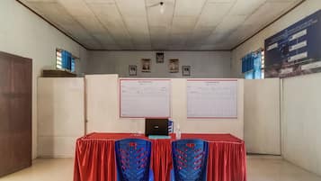 Una habitación con mostrador de recepción, dos sillas azules, una computadora portátil y dos carteles grandes en la pared.