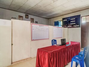 A conference room with a red table, blue chairs, and framed documents on the walls.