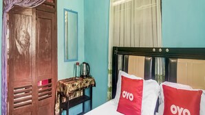 Een hotelkamer met een bed, een tafel met waterkoker en een kledingkast.