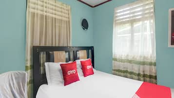 Una habitación de hotel con cama, cortinas, cabecero y un reloj de pared.