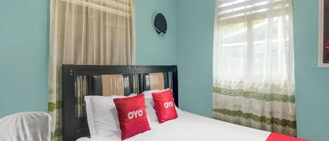 A hotel room with a bed, curtains, a headboard, and a wall clock.
