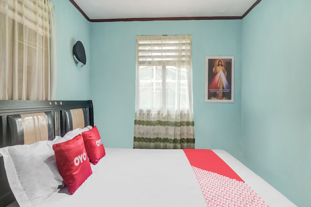 Une chambre à coucher avec un lit, une fenêtre avec des rideaux, une affiche accrochée au mur et une tête de lit.