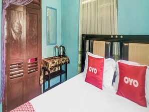 Une chambre d’hôtel avec un lit, une table avec une bouilloire et une armoire.