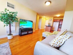 Relax in this cozy living space with a flat-screen TV, comfortable sofa, and a potted plant.
