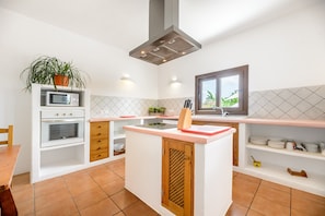 Una cocina moderna con una isla central, horno empotrado, microondas y ventana con vistas.