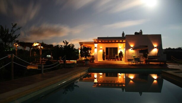 Um edifício com piscina, área de estar externa e céu iluminado pela lua.