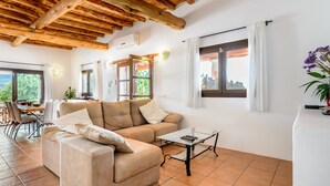 Uma sala de estar com sofá, mesa de centro e um espaço de jantar com cadeiras e mesa.
