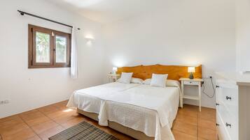 Une chambre à coucher avec un lit, des tables de chevet, une lampe, une fenêtre et une tête de lit en bois.