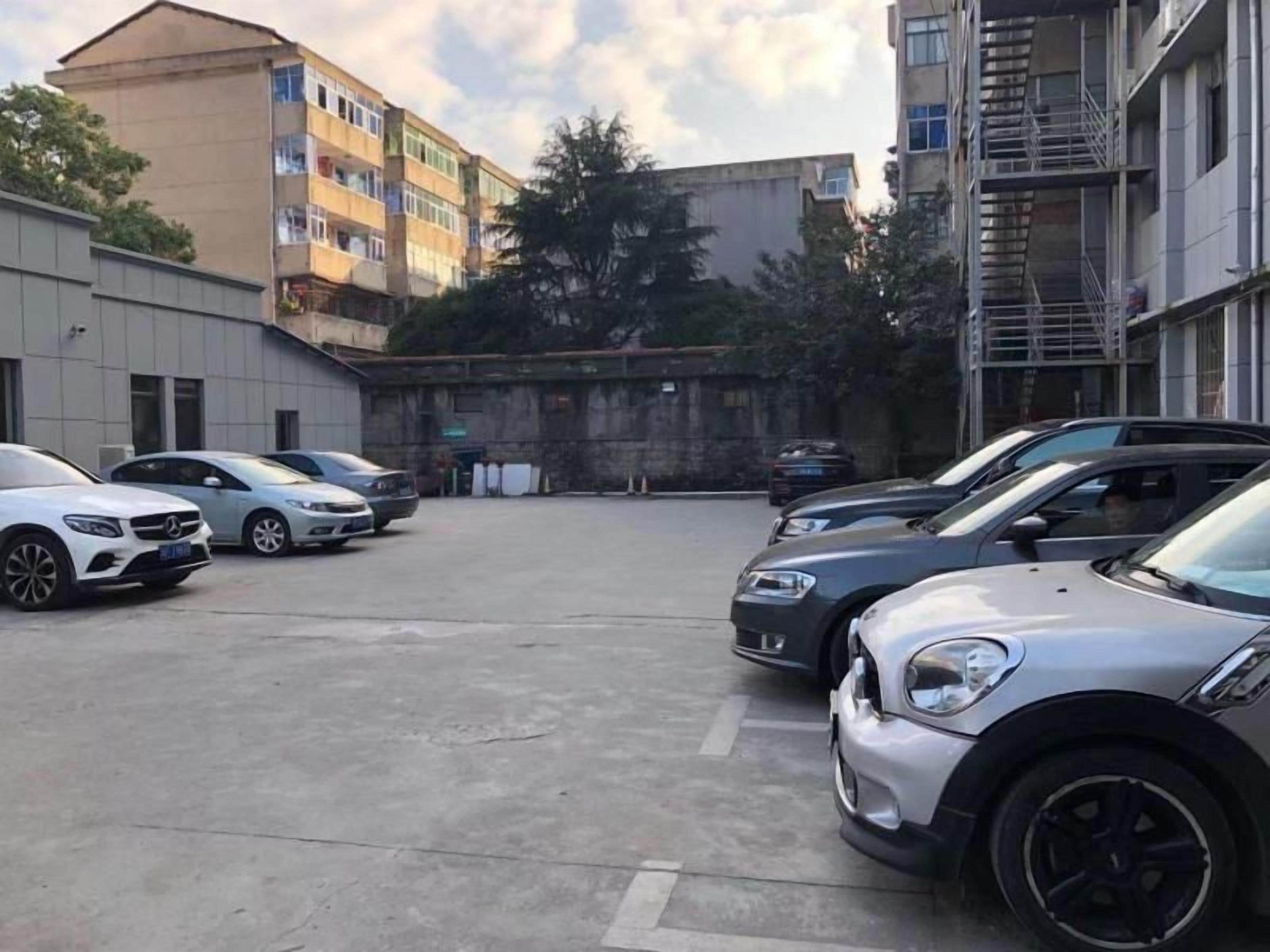 A parking lot with several cars, a building with multiple floors, and a fire escape on the right.
