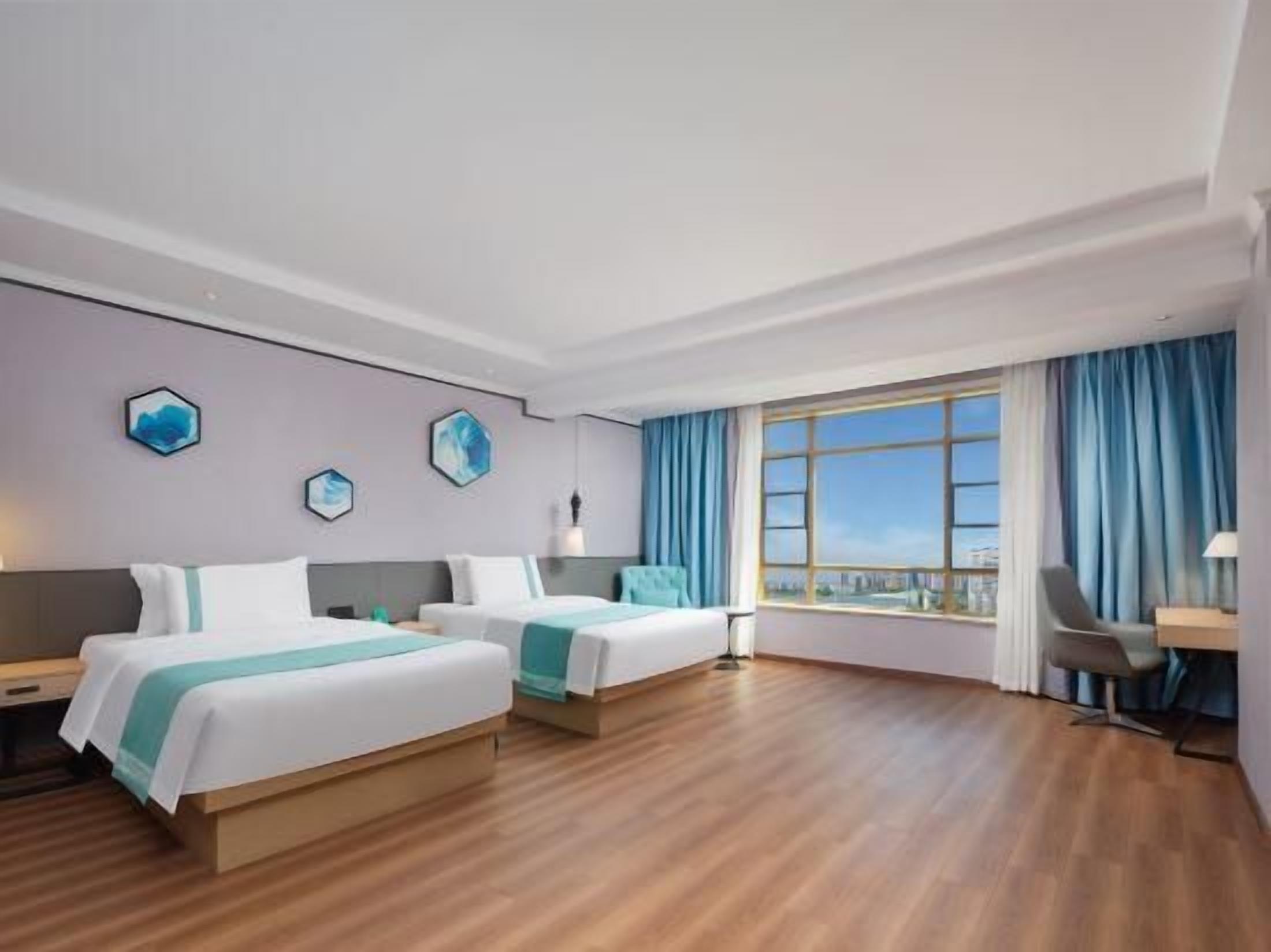 Ett hotellrum med två sängar, ett skrivbord och ett stort fönster med gardiner.