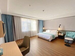 A hotel room with a bed, a desk, a chair, a bedside table, and a lamp. - Greentree Inn Fuzhou Linchuan Yizhong (Fuzhou)