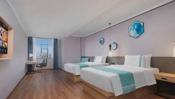 A hotel room with two beds, a desk, and a view of the city.