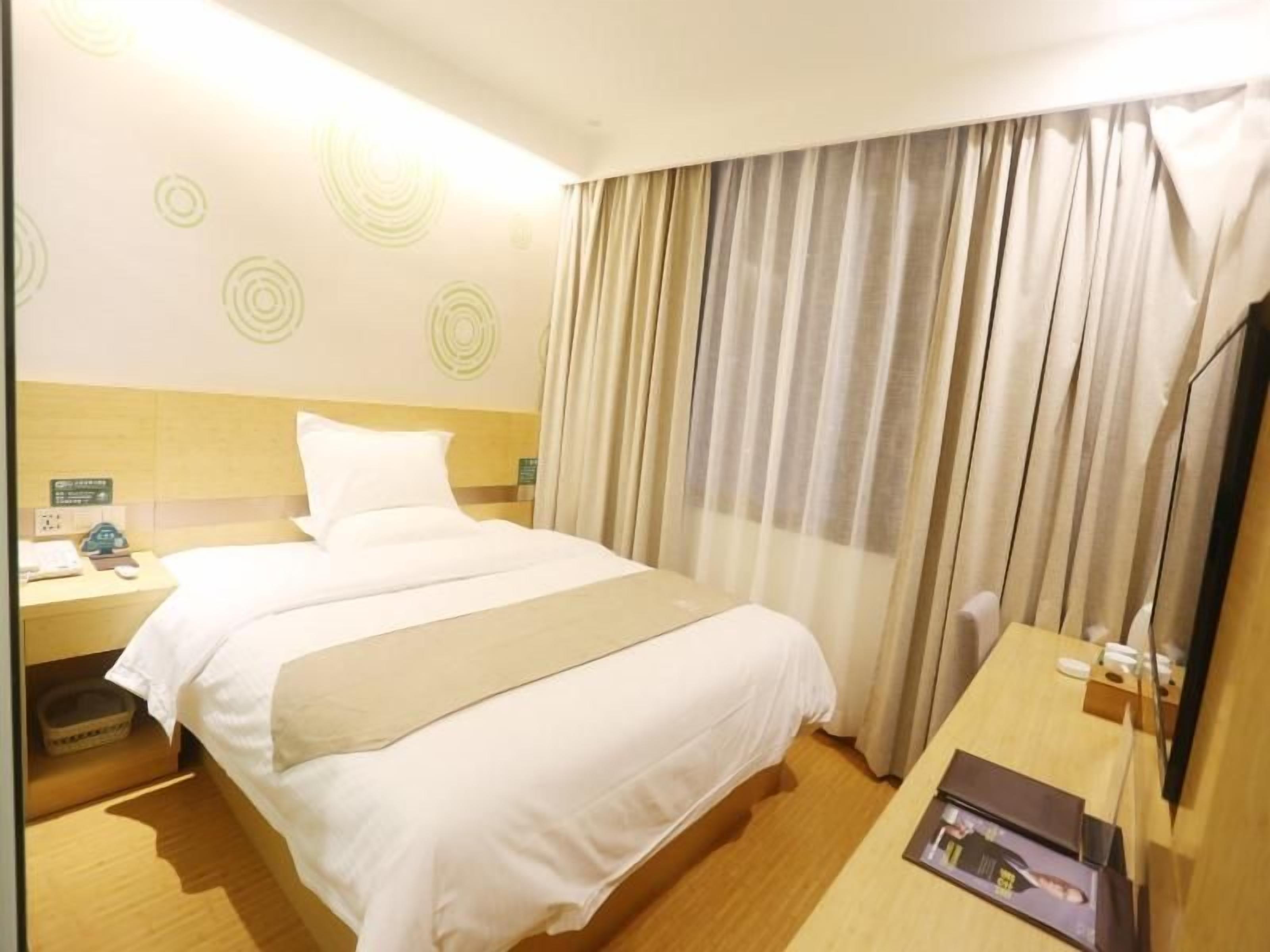 A hotel room with a bed, a nightstand, a desk, and a television.