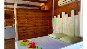 Una habitación tipo cabaña de madera con cama, almohadas y un equipo de aire acondicionado.