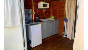 Una cocina compacta con microondas, lavamanos y un refrigerador pequeño.